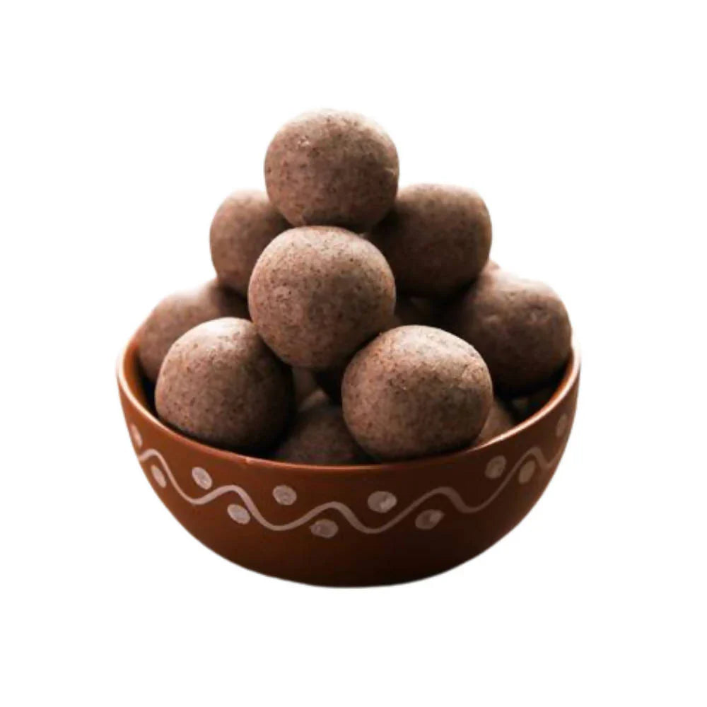 A bowl of millet laddu arranged neatly in a rustic brown bowl. The round, golden-brown laddus have a coarse texture, indicating the use of healthy millet flour mixed with jaggery and ghee. The earthy tone of the bowl complements the natural look of the laddus, making them appear wholesome and nutritious