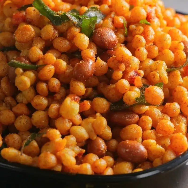 A close-up of Karaboondhi, a traditional South Indian snack, featuring a crunchy mix of tiny fried chickpea flour balls. The golden-brown boondhi pieces are light and crispy, scattered on a plate. Their texture is perfectly crunchy, making them an irresistible savory snack, suitable for munching at any time of the day. The simple yet flavorful ingredients highlight its traditional appeal.